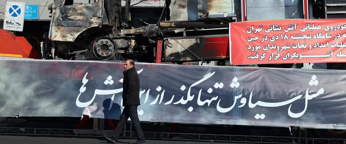 TEHRAN (IRAN(Islamic Republic Of)), 16/01/2026.- An Iranian man walks next to the wreckage of a fire fighter vehicle that burned during anti‑government protests in a street in Tehran, Iran, 16 January 2026. The country remains under a near-total nationwide internet blackout that began on 08 January, amid an intensifying wave of anti-government protests. (Protestas, Teherán) EFE/EPA/ABEDIN TAHERKENAREH
