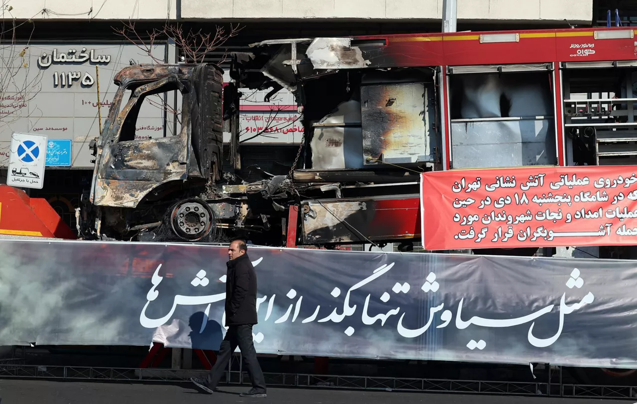 TEHRAN (IRAN(Islamic Republic Of)), 16/01/2026.- An Iranian man walks next to the wreckage of a fire fighter vehicle that burned during anti‑government protests in a street in Tehran, Iran, 16 January 2026. The country remains under a near-total nationwide internet blackout that began on 08 January, amid an intensifying wave of anti-government protests. (Protestas, Teherán) EFE/EPA/ABEDIN TAHERKENAREH
