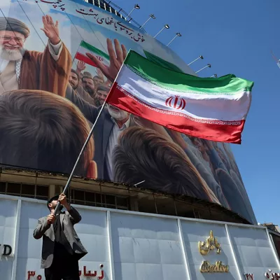 TEHRAN (IRAN(Islamic Republic Of)), 10/04/2026.- An Iranian man waves Iran's national flag in front of a large billboard showing a portrait of the late Iranian Supreme Leader Ayatollah Ali Khamenei at Valiasr Square in Tehran, Iran, 10 April 2026. Iran and the US are expected to hold negotiations in Islamabad, Pakistan, following a recently agreed ceasefire. (Teherán) EFE/EPA/ABEDIN TAHERKENAREH

