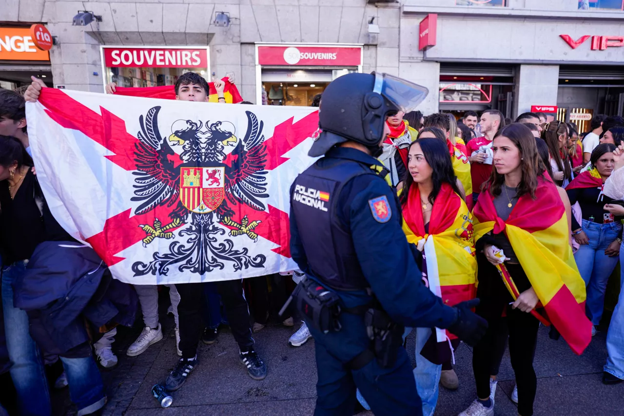 Madrid, 12/10/2026.- La Policía Nacional ha desplegado este lunes un cordón en torno a la acampada de la Puerta del Sol después de que un grupo de manifestantes con banderas de España y al grito de "Ceuta no se vende", se hayan concentrado también en este punto. EFE/Borja Sánchez Trillo
