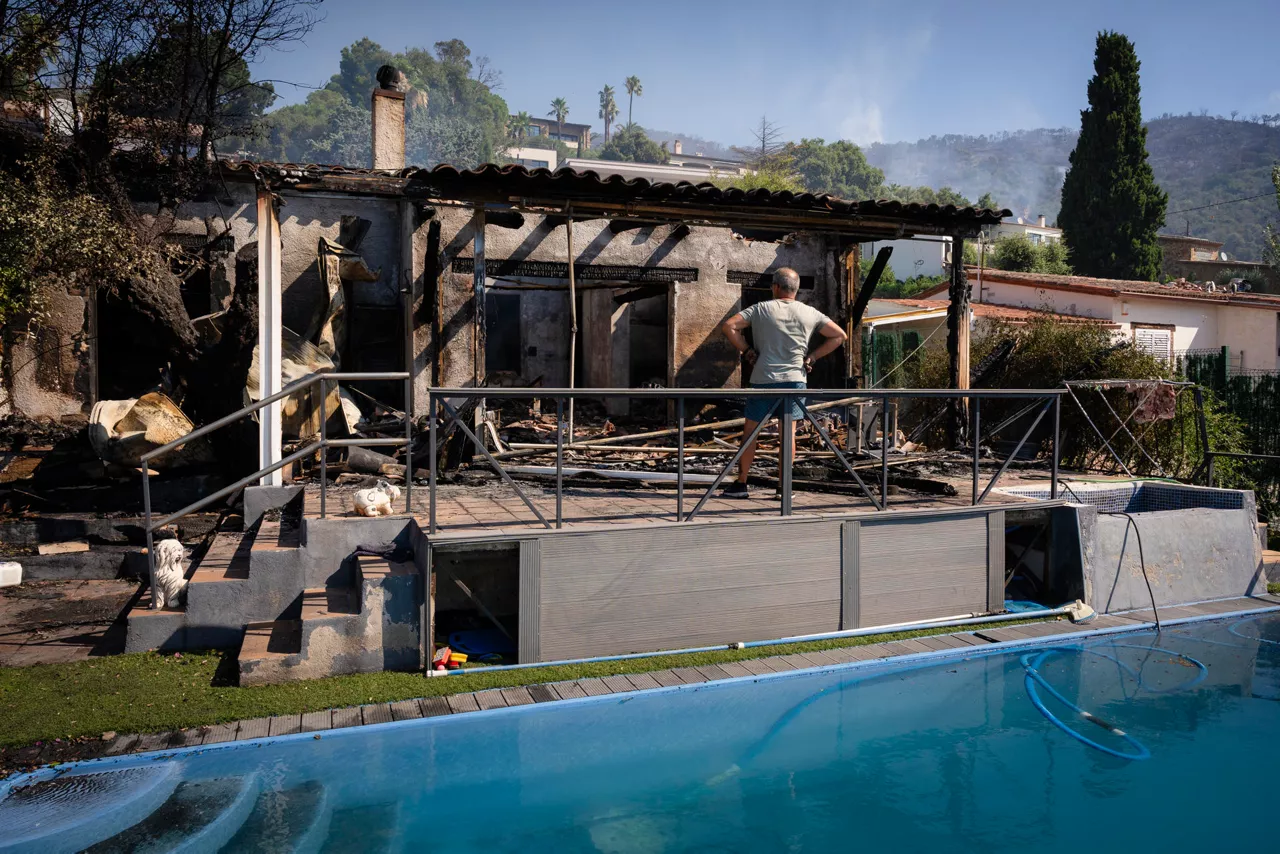 FOTODELDIA CALONGE (GIRONA), 04/07/2026.- Un hombre contempla los restos de una vivienda calcinada en la localidad de Calonge este sábado tras el incendio forestal que comenzó ayer en La Bisbal de l'Empordà (Girona). EFE/David Borrat
